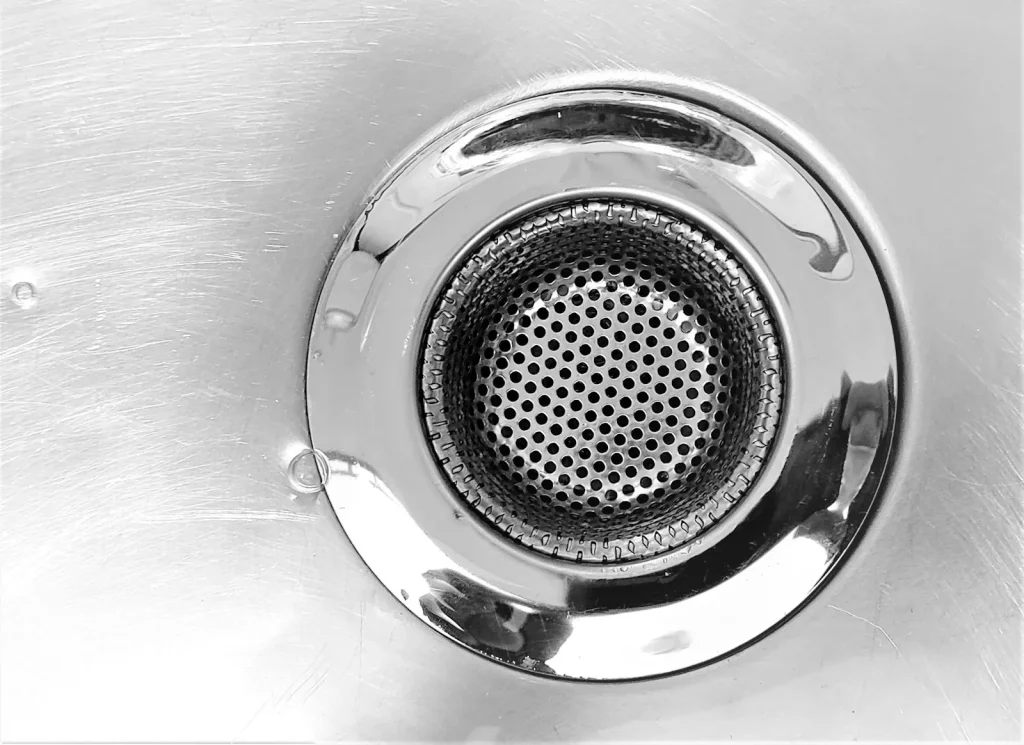 Close-up of a metal sink drain that can block with grease and debris